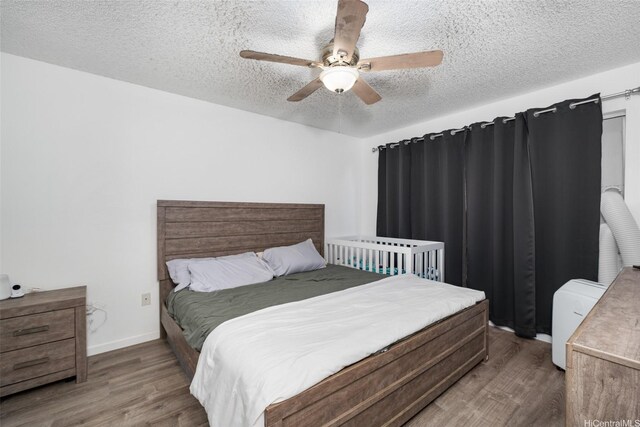 bedroom with a textured ceiling, ceiling fan, baseboards, and wood finished floors