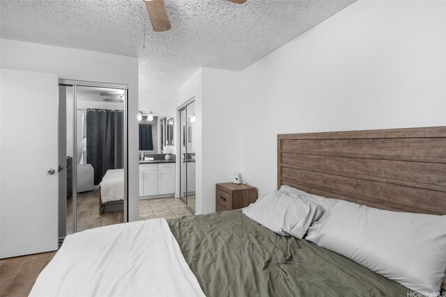 bedroom with a textured ceiling, a ceiling fan, ensuite bathroom, light wood-type flooring, and a closet