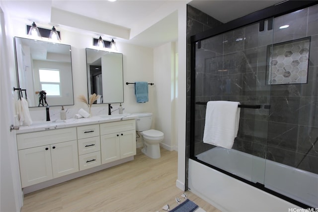 bathroom with double vanity, wood finished floors, toilet, and a sink