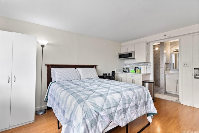 bedroom featuring light wood-style flooring and ensuite bath