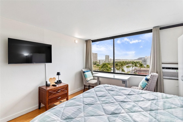 bedroom with baseboards, a city view, and wood finished floors