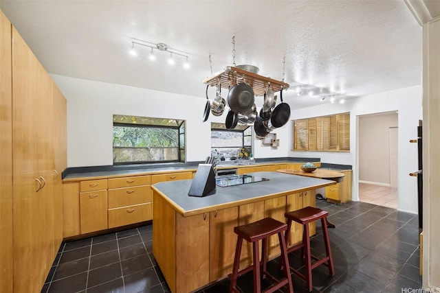 2168 Round Top Dr, Honolulu, HI 96822 - kitchen featuring dark tile patterned floors, rail lighting, a breakfast bar area, and a kitchen island