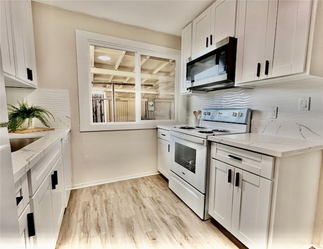 kitchen with stainless steel microwave, white electric stove, white cabinets, light wood-style flooring, and light stone countertops