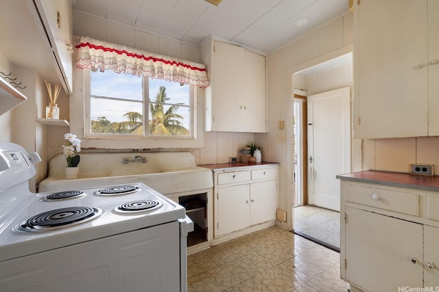 kitchen with white cabinets, light tile patterned flooring, and white electric stove