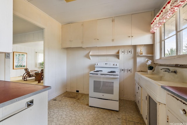 kitchen with cream cabinetry, a sink, light countertops, and white electric range