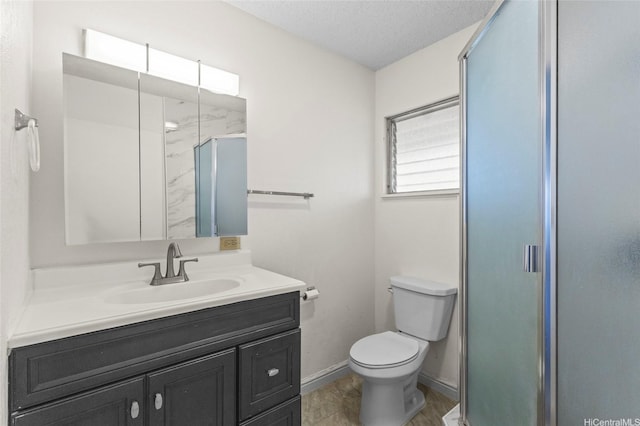 full bathroom featuring toilet, vanity, baseboards, a textured ceiling, and a stall shower