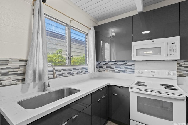 kitchen featuring dark cabinets, white appliances, a sink, and tasteful backsplash