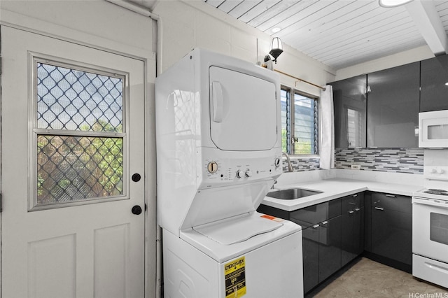 clothes washing area featuring stacked washer / drying machine, wood ceiling, a sink, and laundry area
