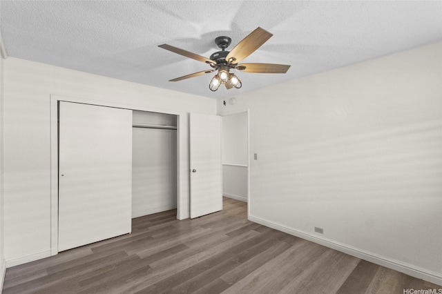 unfurnished bedroom with wood finished floors, a closet, baseboards, and ceiling fan