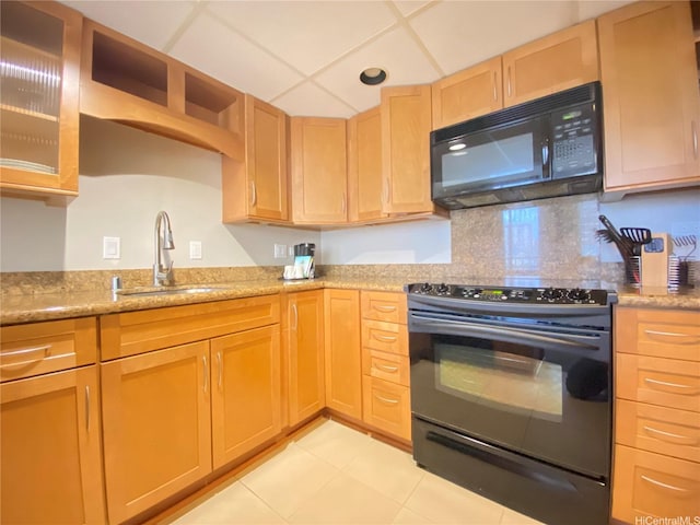 kitchen featuring light brown cabinetry, light stone counters, light tile patterned floors, a sink, and black appliances