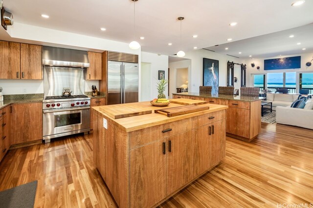 53-926 Kamehameha Hwy, Hauula, HI 96717 - kitchen featuring high end appliances, light wood-style floors, open floor plan, wall chimney range hood, and a center island