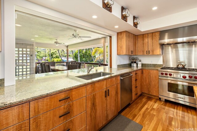 53-926 Kamehameha Hwy, Hauula, HI 96717 - kitchen with wood finished floors, wall chimney range hood, light stone counters, a sink, and appliances with stainless steel finishes