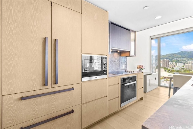 1000 Auahi St Unit 2410, Honolulu, HI 96814 - kitchen with black appliances, light wood-type flooring, light countertops, a mountain view, and recessed lighting