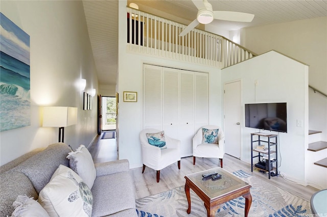 living area featuring high vaulted ceiling, ceiling fan, stairs, and wood finished floors