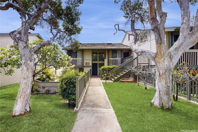 exterior space featuring a lawn, stairs, and fence