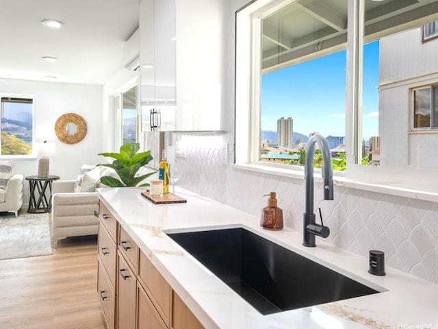 1129 Ala Aloalo St, Honolulu, HI 96818 - kitchen featuring light brown cabinetry, a sink, light wood-style floors, light stone countertops, and tasteful backsplash