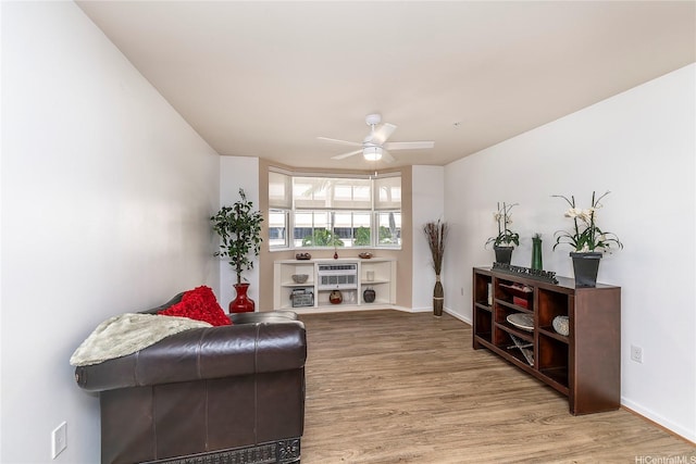 living area with a ceiling fan, baseboards, and wood finished floors