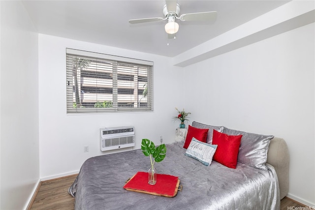 bedroom with wood finished floors, baseboards, and an AC wall unit