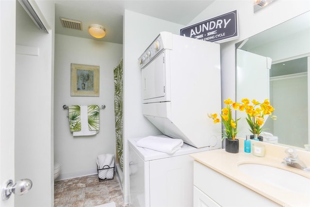 laundry area featuring laundry area, visible vents, a sink, baseboards, and stacked washer and dryer