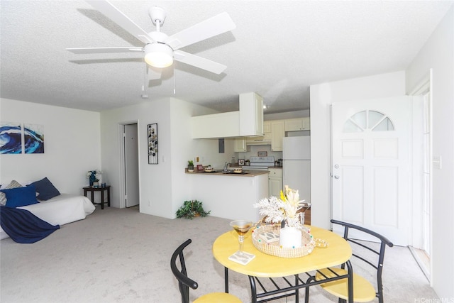 dining area with light colored carpet, ceiling fan, and a textured ceiling