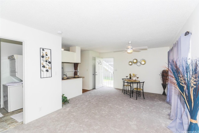 dining room featuring a textured ceiling, a ceiling fan, light colored carpet, and washer / clothes dryer