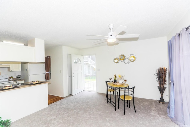 dining space with a ceiling fan and light colored carpet