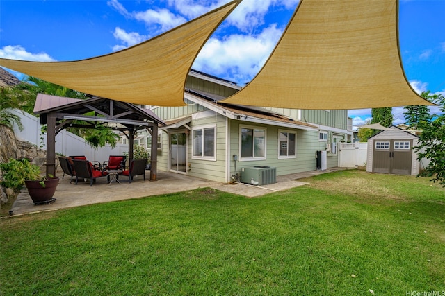 rear view of property featuring a gazebo, a patio area, a storage shed, a fenced backyard, and a yard