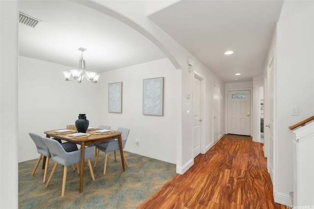 dining space with arched walkways, visible vents, recessed lighting, a notable chandelier, and wood finished floors