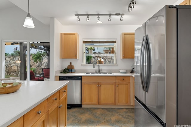 kitchen featuring decorative light fixtures, appliances with stainless steel finishes, a sink, and light countertops