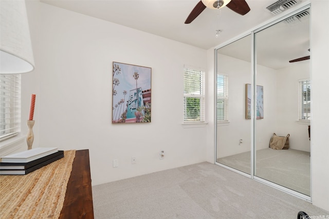 unfurnished bedroom with a closet, carpet, visible vents, and ceiling fan