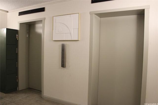 hallway with elevator, a textured ceiling, and light tile patterned floors
