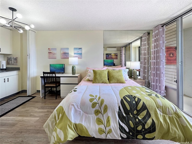 bedroom with wood finished floors, a textured ceiling, and a chandelier
