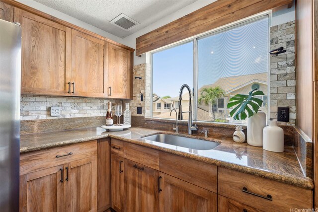 91-1057 Laaulu St Unit 4B, Ewa Beach, HI 96706 - kitchen featuring visible vents, freestanding refrigerator, stone countertops, a sink, and backsplash