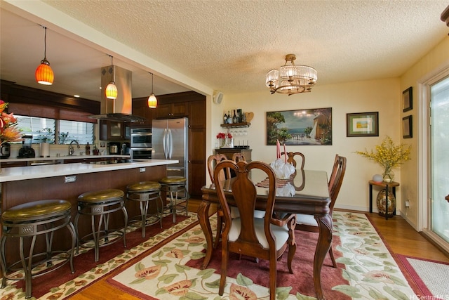 dining space featuring a wealth of natural light, wood finished floors, and a textured ceiling