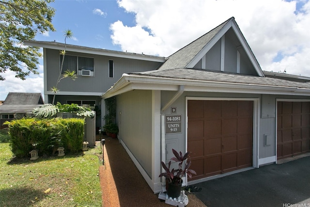 view of front facade featuring a garage, roof with shingles, a front yard, and driveway