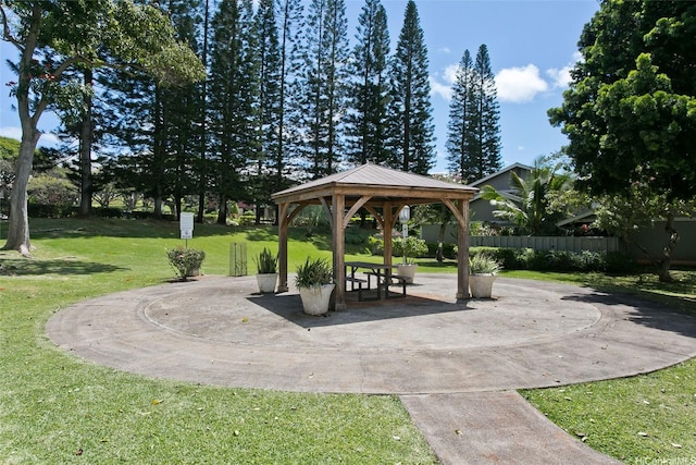 view of community with a gazebo, a lawn, and fence