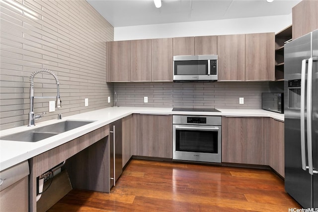 kitchen featuring light countertops, modern cabinets, a sink, black appliances, and tasteful backsplash