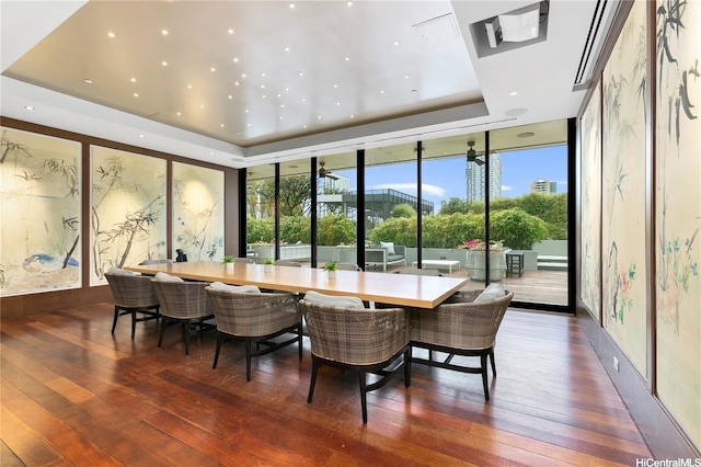 dining area with expansive windows, recessed lighting, wood-type flooring, and a raised ceiling