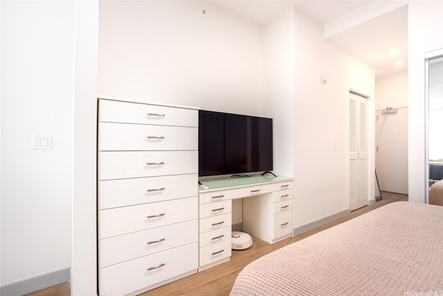 bedroom with light wood-type flooring, baseboards, and built in desk