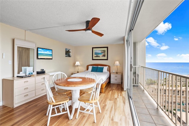 2427 Kuhio Ave Unit 2205, Honolulu, HI 96815 - interior space featuring light wood finished floors, a ceiling fan, a textured ceiling, and a water view