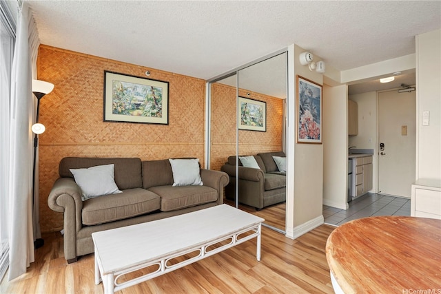 2427 Kuhio Ave Unit 2205, Honolulu, HI 96815 - living room featuring an accent wall, a textured ceiling, light wood finished floors, and baseboards
