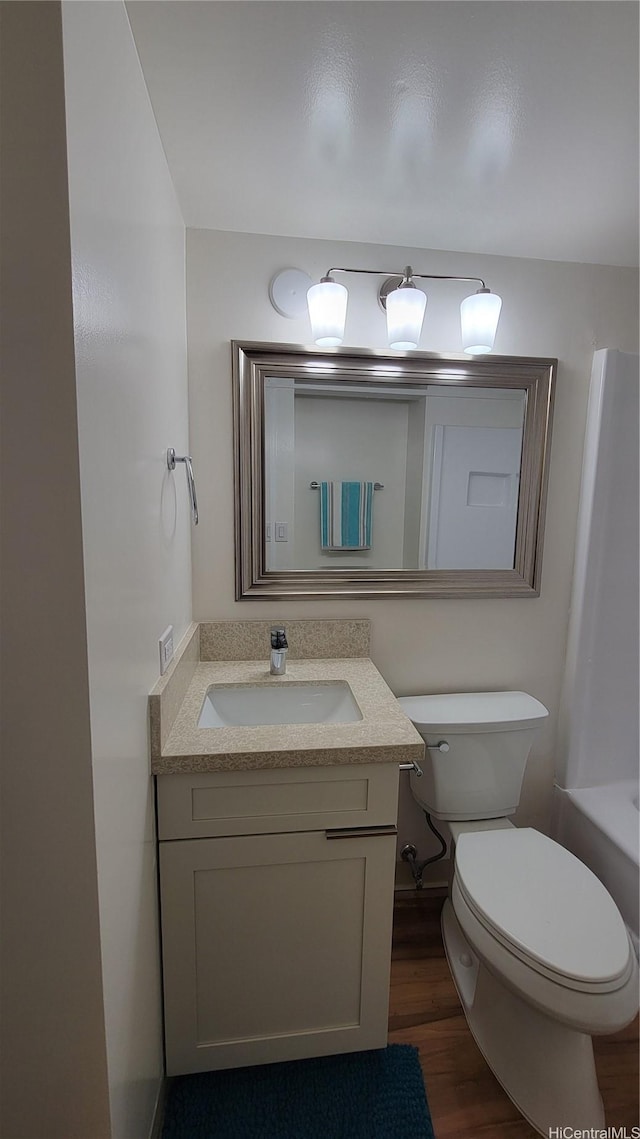 full bathroom with a tub to relax in, wood finished floors, toilet, and vanity
