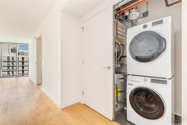 washroom with light wood-type flooring, baseboards, stacked washer and clothes dryer, and laundry area