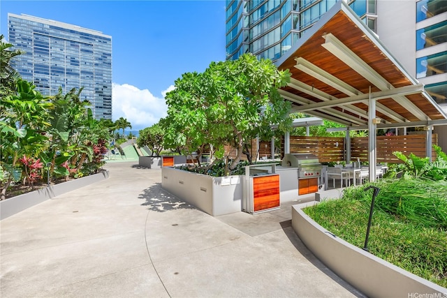 view of community with exterior kitchen, a patio area, and fence
