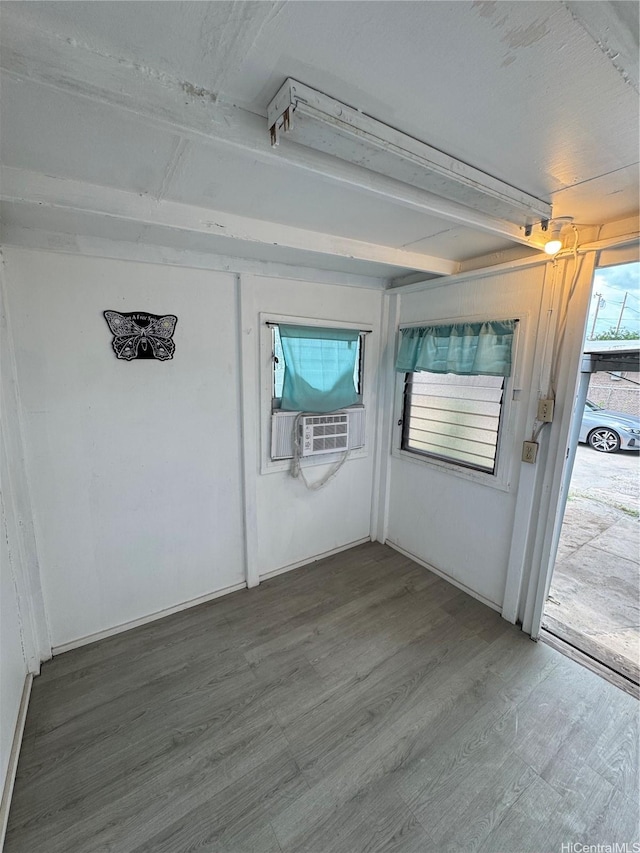 unfurnished room with cooling unit, beam ceiling, and wood finished floors