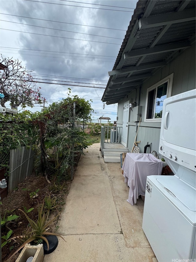 view of patio with fence and stacked washer / dryer