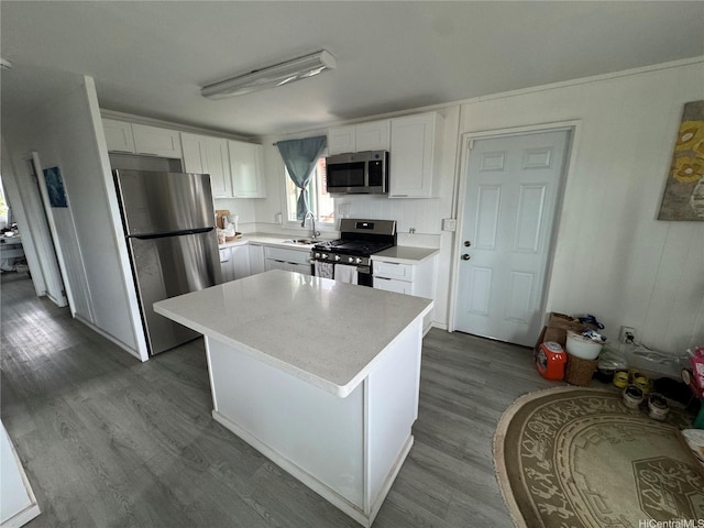kitchen with a sink, dark wood-style flooring, stainless steel appliances, white cabinetry, and light countertops