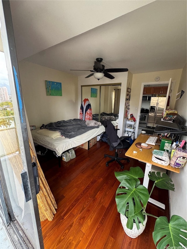 bedroom featuring stainless steel fridge, a closet, ceiling fan, and wood finished floors