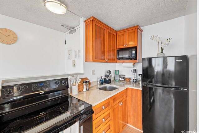 2427 Kuhio Ave Unit 906, Honolulu, HI 96815 - kitchen featuring black appliances, brown cabinets, light stone counters, a textured ceiling, and wood finished floors