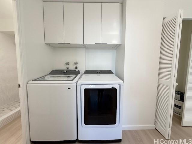 laundry area with washing machine and clothes dryer, cabinet space, light wood finished floors, and baseboards